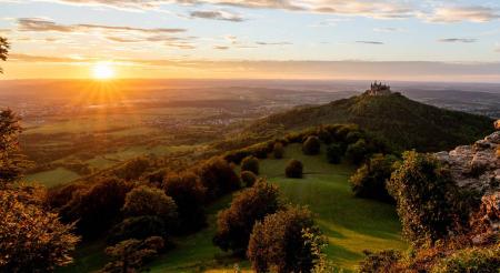 Sonnenuntergang über der Burg Hohenzollern in einer idyllischen Landschaft